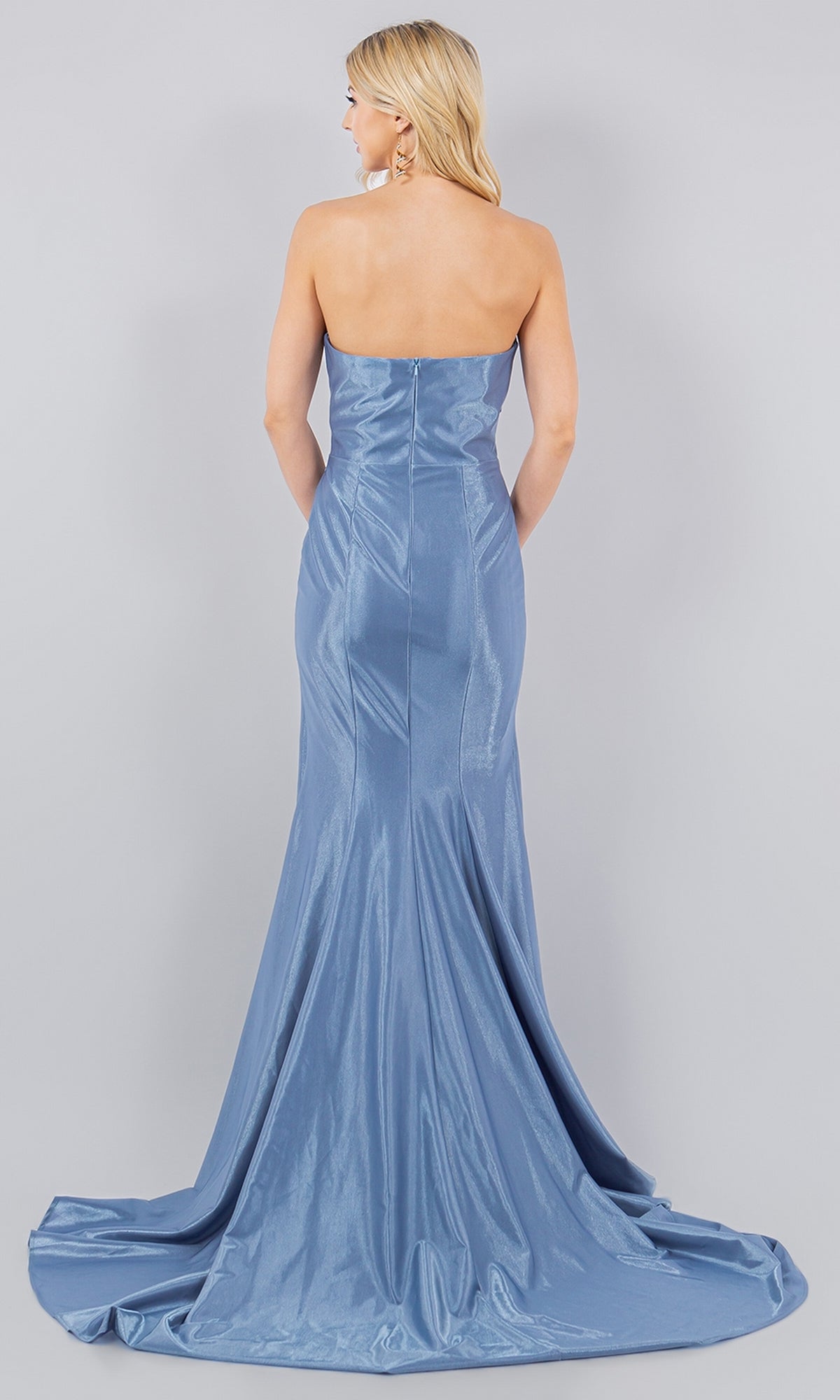 A blonde woman is seen from behind wearing the Satin Mermaid Prom Dress: Cinderella Couture 8083J, a strapless light blue gown with a slight train, set against a plain gray background.